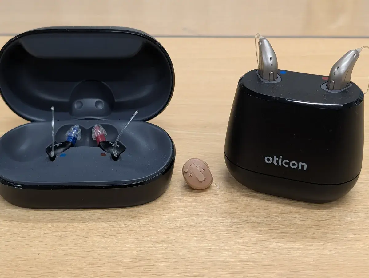当店で取り扱うオーティコンの補聴器。左からZealと充電ケース、Own、充電器に置いたIntent